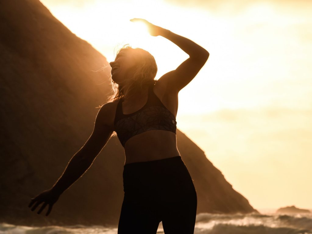 Woman doing yoga on beach at sunset